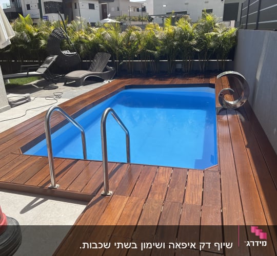 בריכה עם דק עץ וכיסאות נוח בגינה